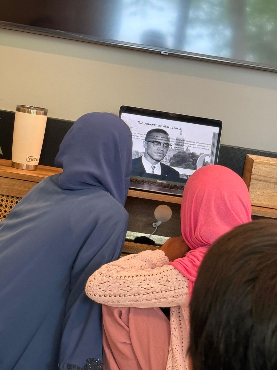 Youth presenting a research project on the journey of Malcolm X